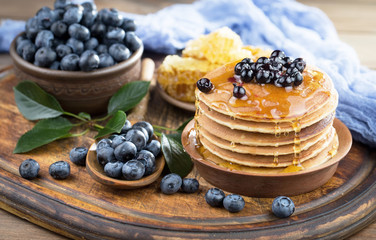 Blueberries in a plate and pancakes, on an old background.