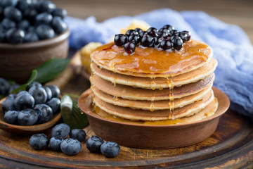 Blueberries in a plate and pancakes, on an old background.