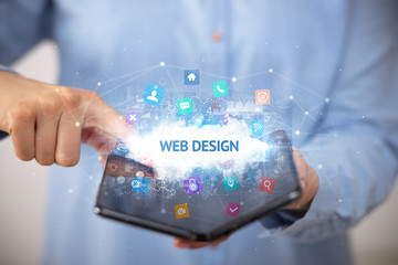 Businessman holding a foldable smartphone with WEB DESIGN inscription, technology concept
