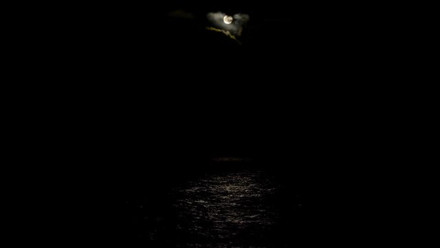 The full moon illuminates the water surface. Moon track on the surface of the water. Nocturnal Sea bright sparkles light water moonlight. Full moon 4K 60Fps