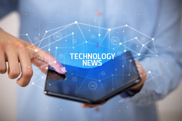 Businessman holding a foldable smartphone with TECHNOLOGY NEWS inscription, new technology concept