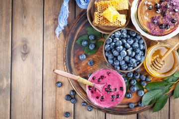 Ripe, fresh blueberries in a wooden bowl on an old background.