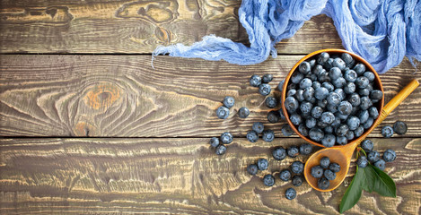 Ripe, fresh blueberries in a wooden bowl on an old background.