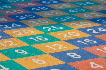Colorful square pattern with numbers painted on the ground in a childrens play area.