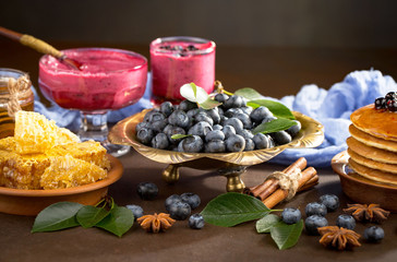 Blueberries in a plate and pancakes, on an old background.