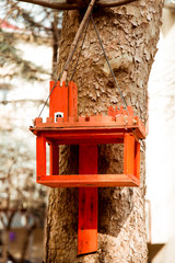 red bird feeder, in the form of a castle, hanging on a tree