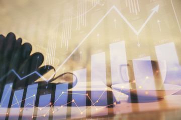 Double exposure of financial chart drawing and desktop with coffee and items on table background. Concept of forex market trading