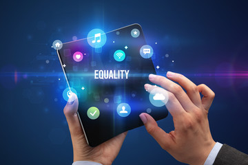 Businessman holding a foldable smartphone with EQUALITY inscription, social media concept