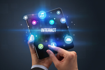 Businessman holding a foldable smartphone with INTERACT inscription, social media concept