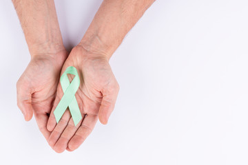 Hands holding green ribbon. White background.