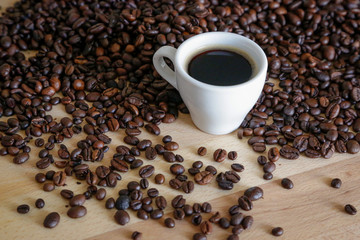  A cup of black coffee with coffee grains, natural light on wooden table