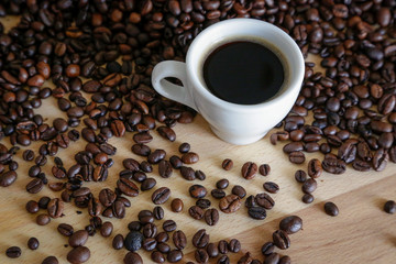  A cup of black coffee with coffee grains, natural light on wooden table