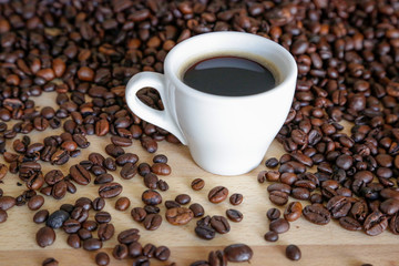 A cup of black coffee with coffee grains, natural light on wooden table