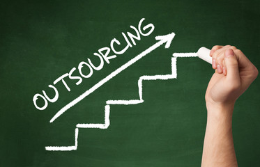 Hand drawing OUTSOURCING inscription with white chalk on blackboard, business concept
