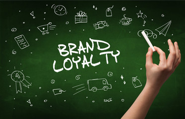 Hand drawing BRAND LOYALTY inscription with white chalk on blackboard, online shopping concept