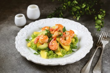 Salad with shrimp tails, lettuce, avocado, mango slice, parsley, olive oil and lemon juice. Healthly food.