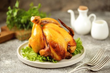 Grilled whole chicken on a gray background.