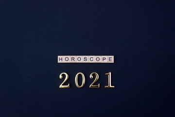 Word Horoscope and 2021 numbers. Wooden blocks with letters on black background. Flat lay, copy space