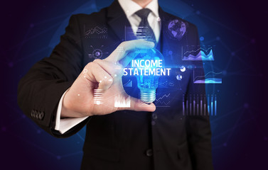 Businessman holding lightbulb with INCOME STATEMENT inscription, Business idea concept