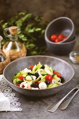 Greek salad with mozzarella. Salad with bell peppers, cherry tomatoes, cucumbers, feta, oregano, olives, onions, olive oil and lemon juice.
