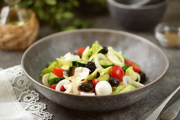 Greek salad with mozzarella. Salad with bell peppers, cherry tomatoes, cucumbers, feta, oregano, olives, onions, olive oil and lemon juice.