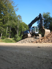 Obraz premium Blauer Bagger auf dem Waldparkplatz