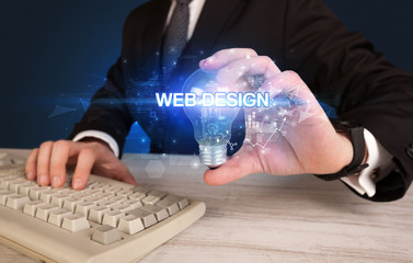 Businessman holding light bulb with WEB DESIGN inscription, innovative technology concept