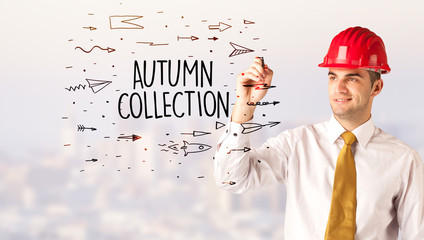 Handsome businessman with helmet drawing AUTUMN COLLECTION inscription, contruction sale concept