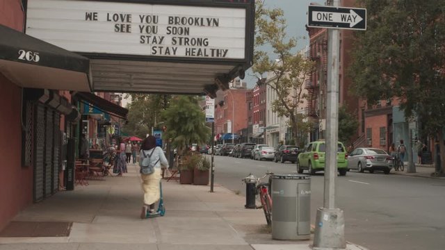 woman skates under hopeful Covid message outside theater in Brooklyn