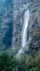 •	Waterfall in Zhangjiajie Grand Canyon, Hunan province. The water flows down from the mountain peak to the canyon. The silk-like smooth water, the cliff, the trees, the blue sky and the reflection ar