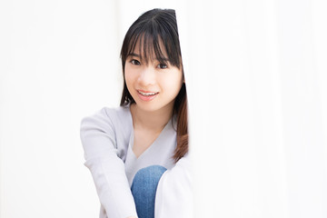 部屋の窓際に座る若い女性