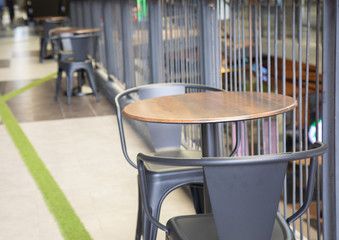 Side view of black round table with two wooden chairs with nobody in modern style department store for meeting, dining and relaxing shows concept of social distance and space for business discussion