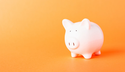 Front small white fat piggy bank, studio shot isolated on orange background and copy space for use,...