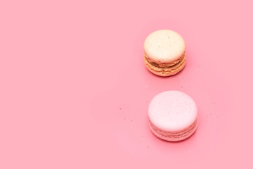 two macaroons pink and beige on a pink background, top view