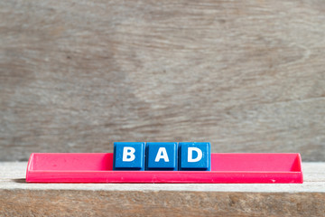Tile letter on red rack in word bad on wood background