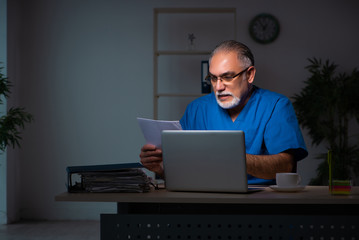 Aged male doctor in the hospital at night