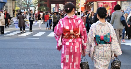 Obraz premium Two young women are dressed in a traditional kimono as they walk down a street in Japan