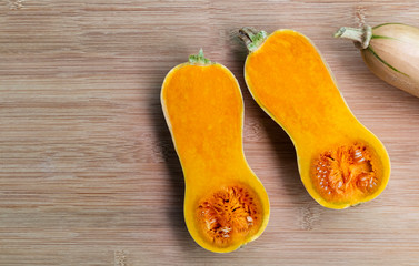 Butternut squash sliced ​​on a wooden table. Butternut is a bell-shape fruit with sweet orange-yellow flesh.