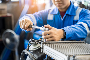 Mechanic Asian man close up fixing repairing car engine automobile vehicle parts examining using tools wrench equipment working hard in workshop garage support and service in overall work uniform