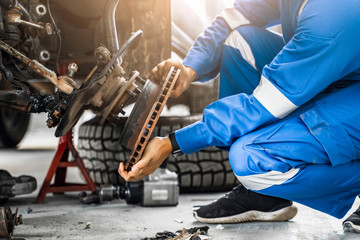 Mechanic Asian man close up fixing repairing car rotor spindle hub automobile vehicle parts examining using tools equipment working hard in workshop garage support and service in overall work uniform