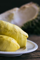 Traditional Thai fruit :Durian,the king of fruit in Thailand on white plate put on wood table. Durian is exotic tropical fruit so delicious, sweet and good smell. Ripe durian has yellow gold colour.