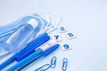 Education or back to school concept. Set of blue school supplies, medical face mask and antiseptic sanitizer gel. New normal during coronavirus pandemic. Virus protection, keep distance. Copy space