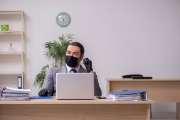 Young male employee in the office during pandemic disease