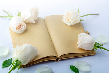 Blank open diary (notebook, sketchbook) decorated with white roses with space for text or lettering. Concept of writing letter, wishes, goals, plans, life story. Flat lay mockup spring composition