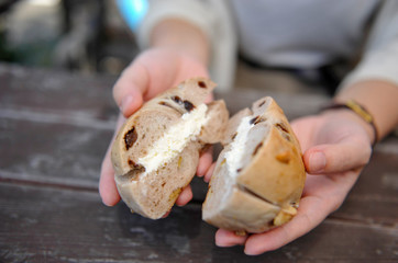 半分に切ったクリームチーズ入りのベーグルと女性の手