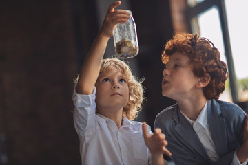 Two boys looking at the jar with coins