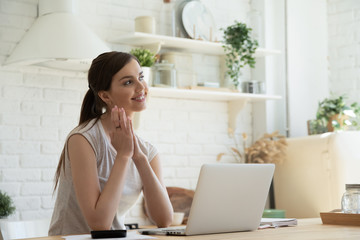 Lost in dreams. Happy inspired young woman teleworker, copywriter or blogger sitting at kitchen...