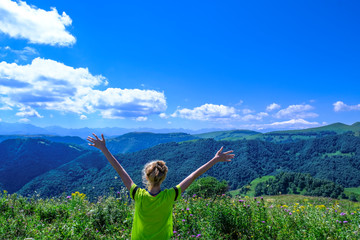 Fototapeta na wymiar young tourist woman raising her hands up and enjoying a fantastic view on nature, forest and alpine mountains. Mountainous landscape