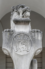 Closeup of stone sculpture of sitting lion with city of Lviv ancient armorial bearing at the entrance of Town Hall, Ukraine