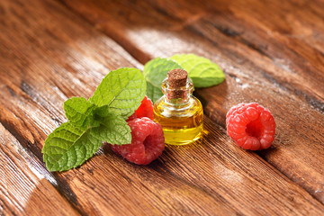 Mint leaves and raspberry berry on a wooden table.